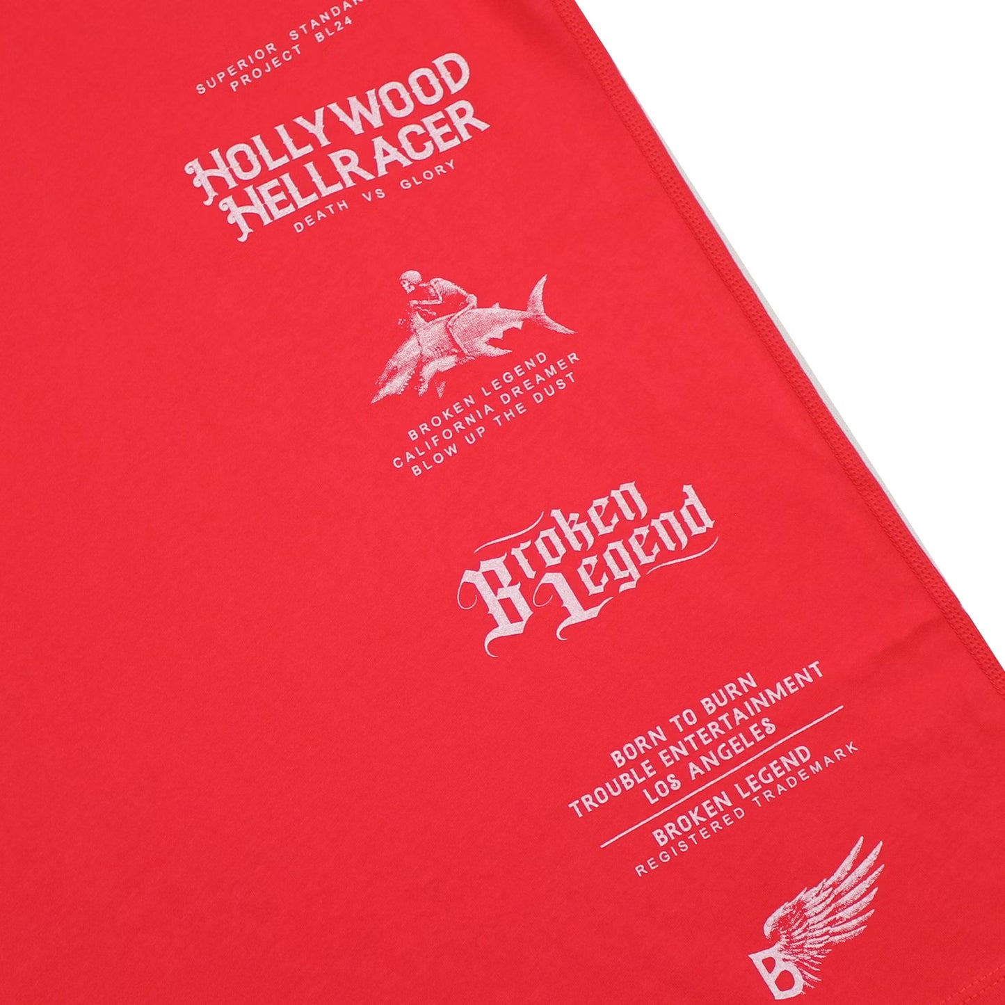 Detailaufnahme des Broken Legend Haifisch-Motivs auf roter Pima-Baumwolle – hochwertiger Siebdruck.