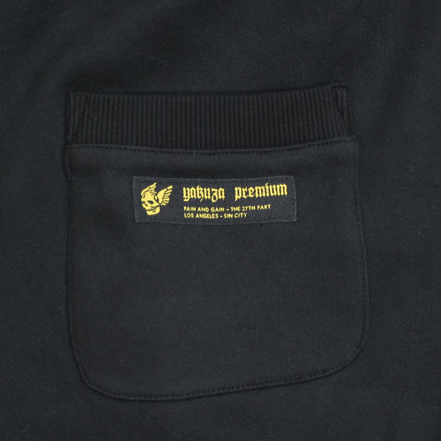 Yakuza Premium Herren Jogginghose Schwarz Detailansicht Gesässtasche mit gelb besticktem Logo-Label und Sin City Schriftzug.