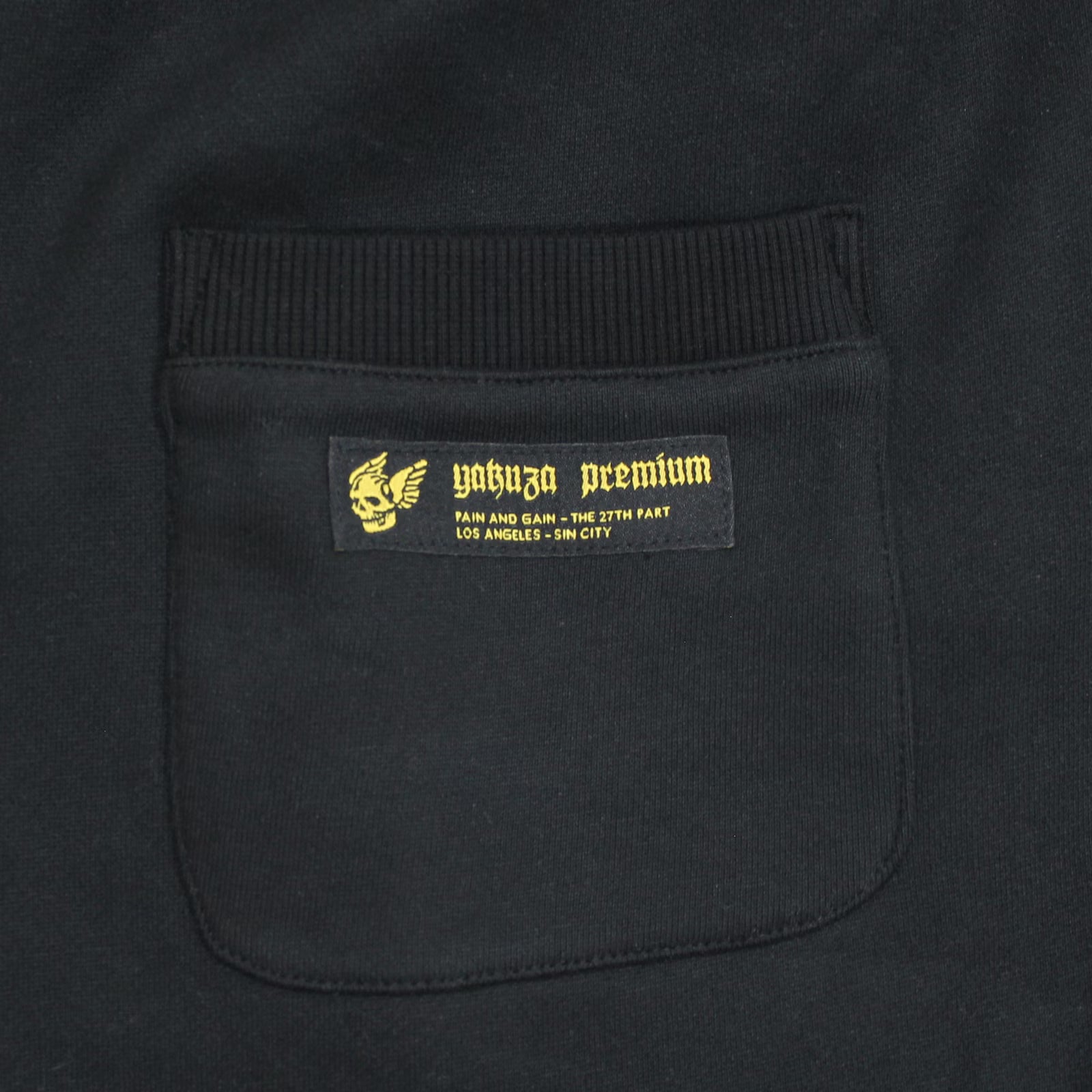 Yakuza Premium Herren Jogginghose Schwarz Detailansicht Gesässtasche mit gelb besticktem Logo-Label und Sin City Schriftzug.