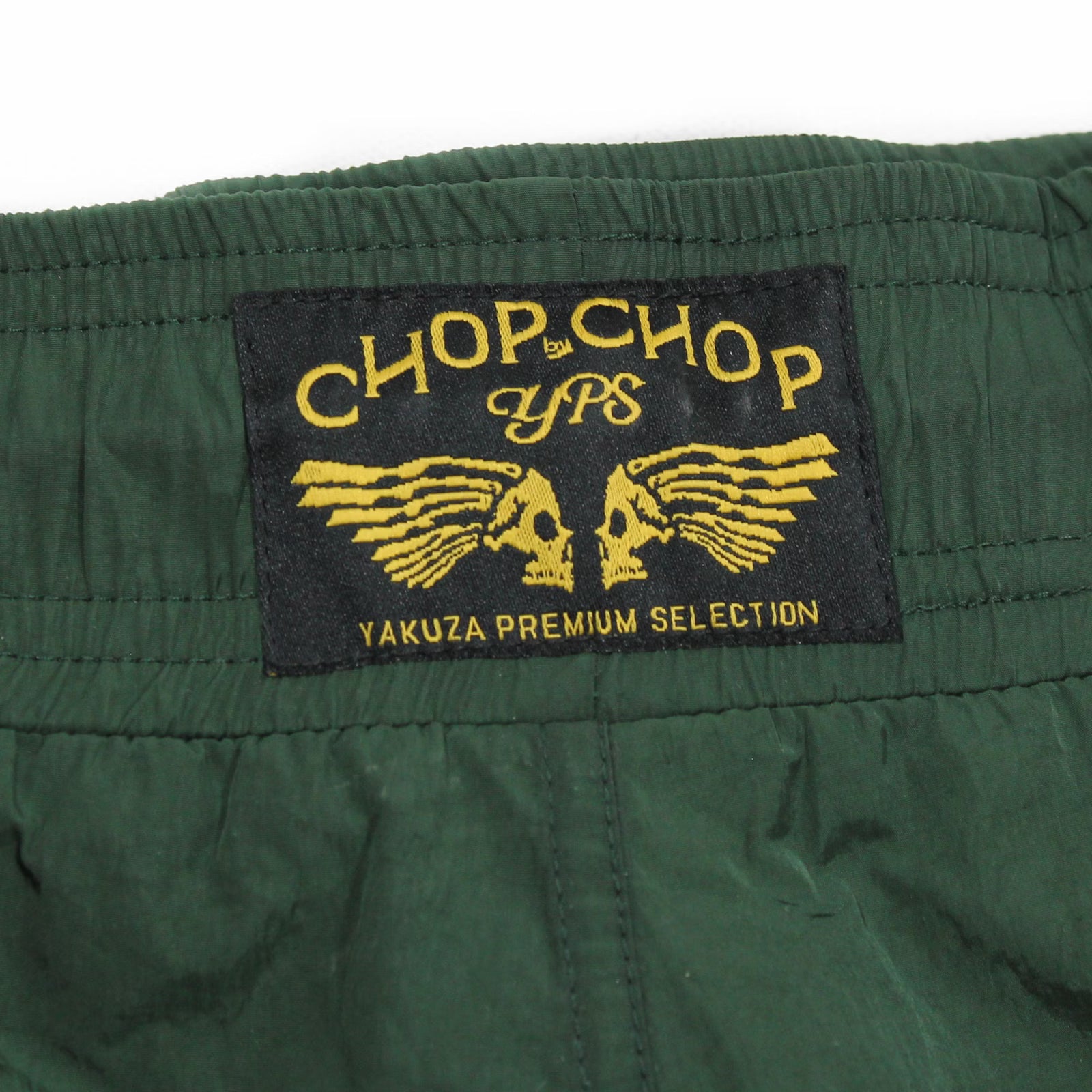 Gewebtes Chop Chop YPS Label der dunkeloliven Yakuza Premium Badeshorts auf der Rückseite.