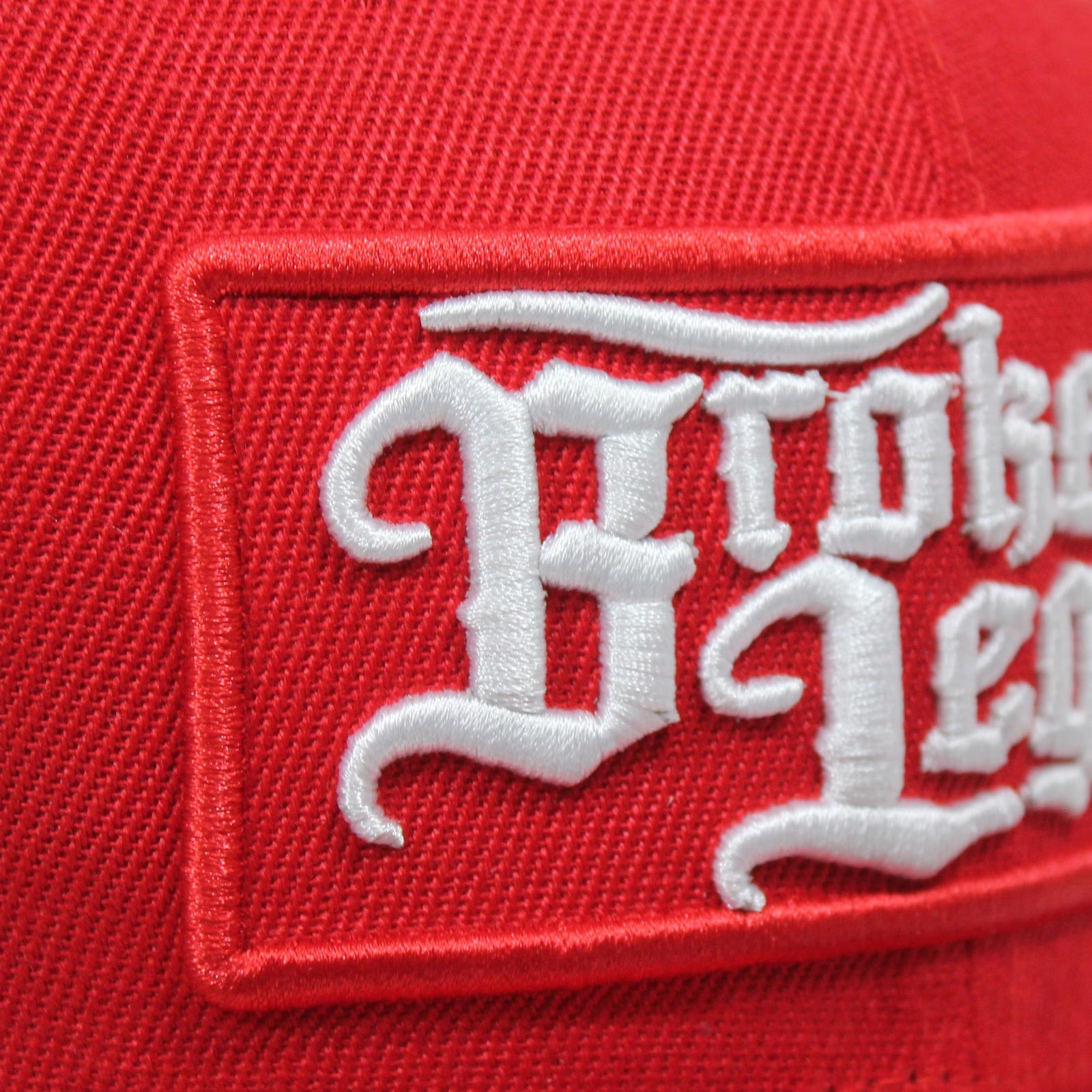 Rotes Broken Legend Cap mit seitlicher Stickerei eines fliegenden Hundes.