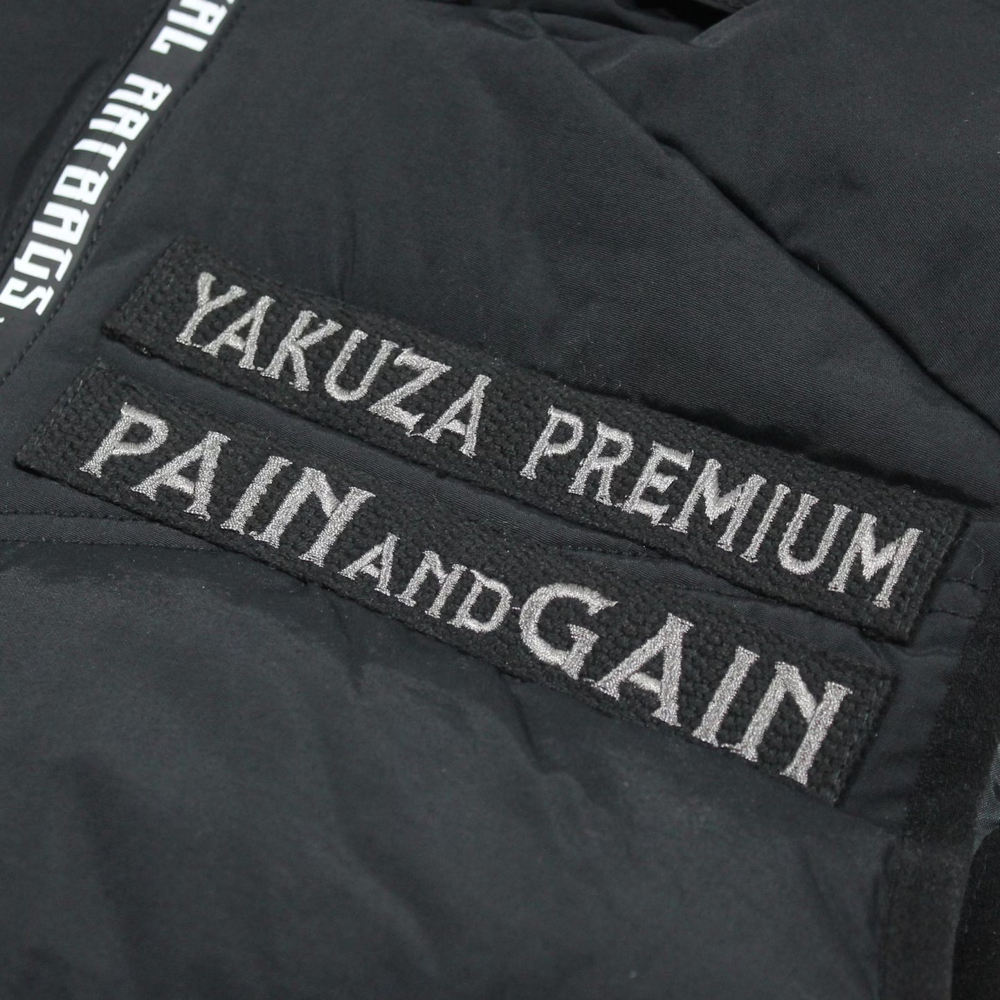 Schwarze Yakuza Premium Weste 3966 mit Harlekin-Print auf dem Rücken und abnehmbarer Kapuze.