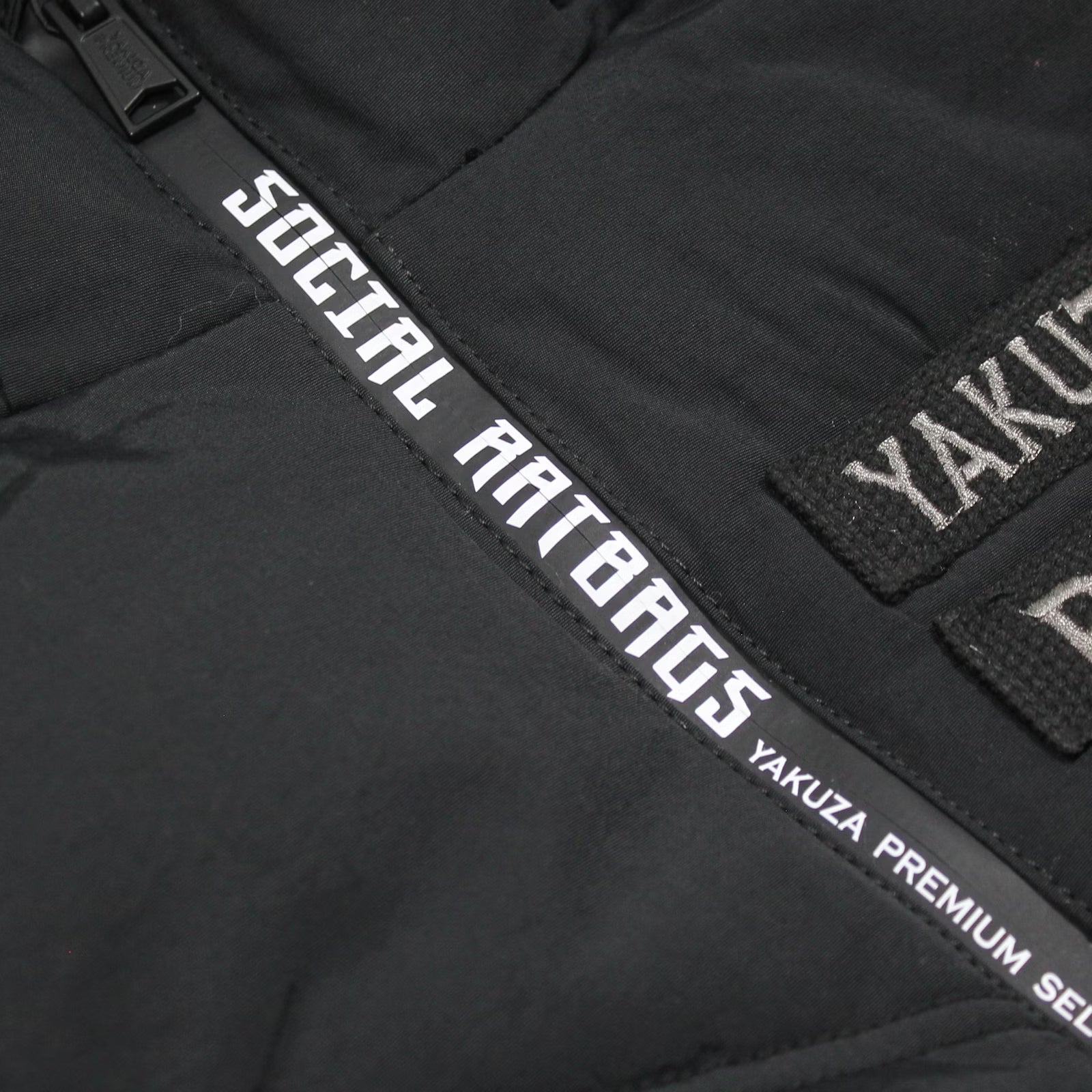 Schwarze Yakuza Premium Weste 3966 mit Harlekin-Print auf dem Rücken und abnehmbarer Kapuze.