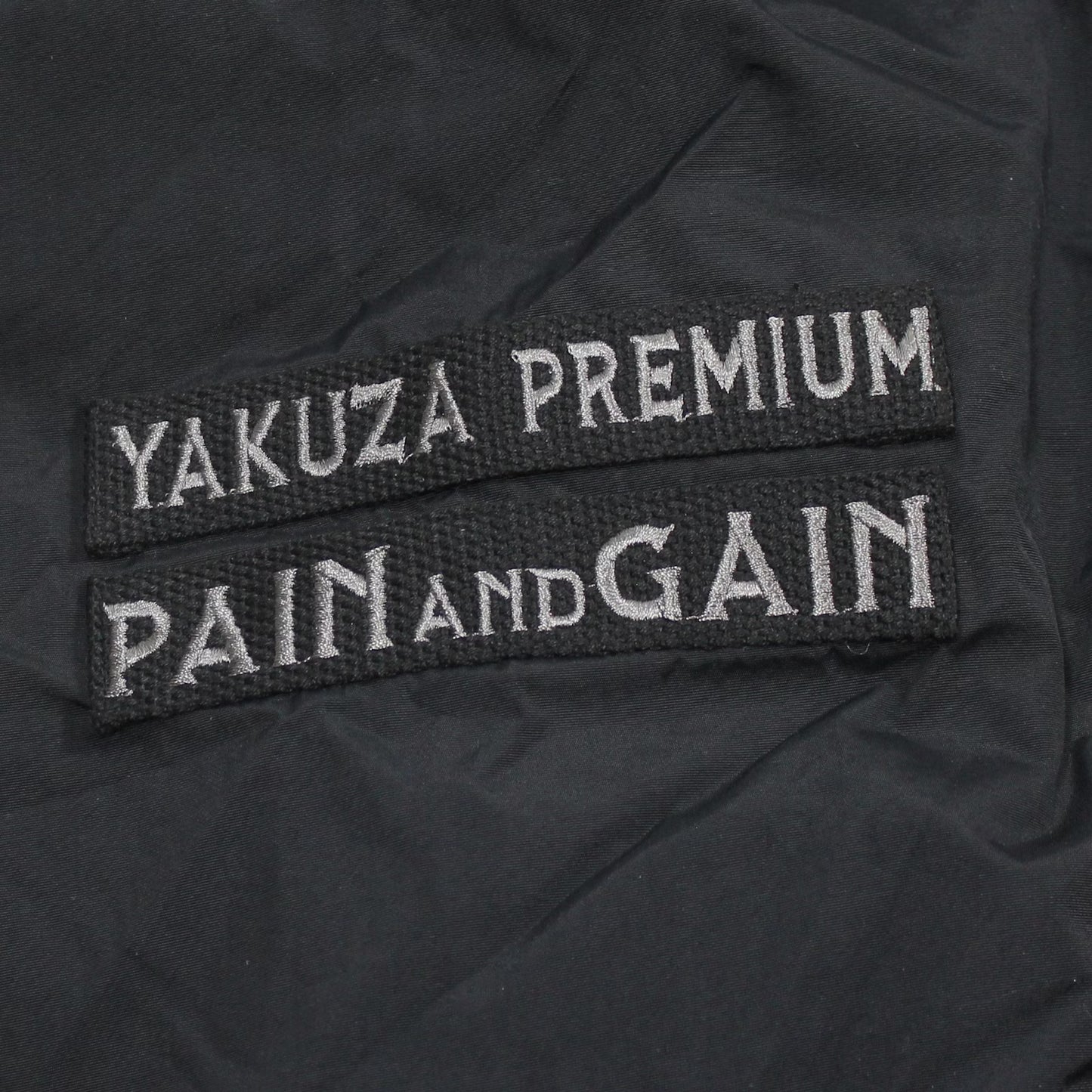 Yakuza Premium Windbreaker 3963 in Schwarz mit Kapuze, Harlekin-Print und Patches.