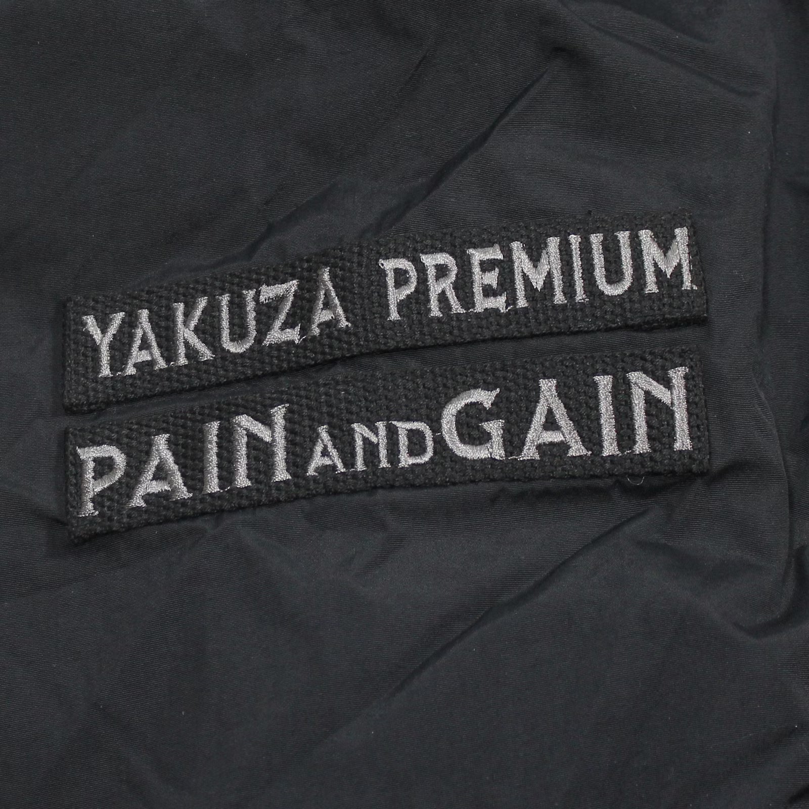Yakuza Premium Windbreaker 3963 in Schwarz mit Kapuze, Harlekin-Print und Patches.